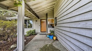 A house with a covered porch, a wooden door, and potted plants. - Home w/ Hot Tub: 7 Mi to Edmonds Waterfront! (Lynnwood)