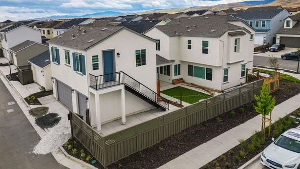 A residential area with modern two-story houses, a gated driveway, and a well-maintained lawn. - California Midterm Rental With Fenced Yard! (Tracy)