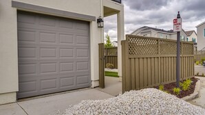 A residential garage with a no parking sign, a wooden fence, and a gravel driveway. - California Midterm Rental With Fenced Yard! (Tracy)