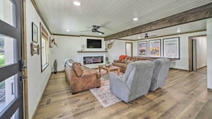 A spacious living room with a fireplace, leather sofas, a flat-screen TV, and a ceiling fan. - Eufaula Retreat w/ Lake Views: Walk to Marina (Eufaula)