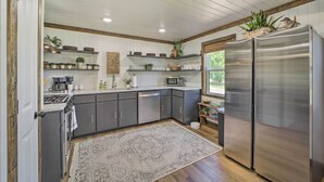 A modern kitchen with grey cabinets, stainless steel appliances, and decorative plants. - Eufaula Retreat w/ Lake Views: Walk to Marina (Eufaula)