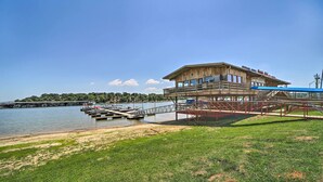 A waterfront building with a dock and a grassy area in front. - Eufaula Retreat w/ Lake Views: Walk to Marina (Eufaula)