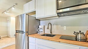 Una cocina moderna con electrodomésticos de acero inoxidable, encimera de madera y armarios blancos.