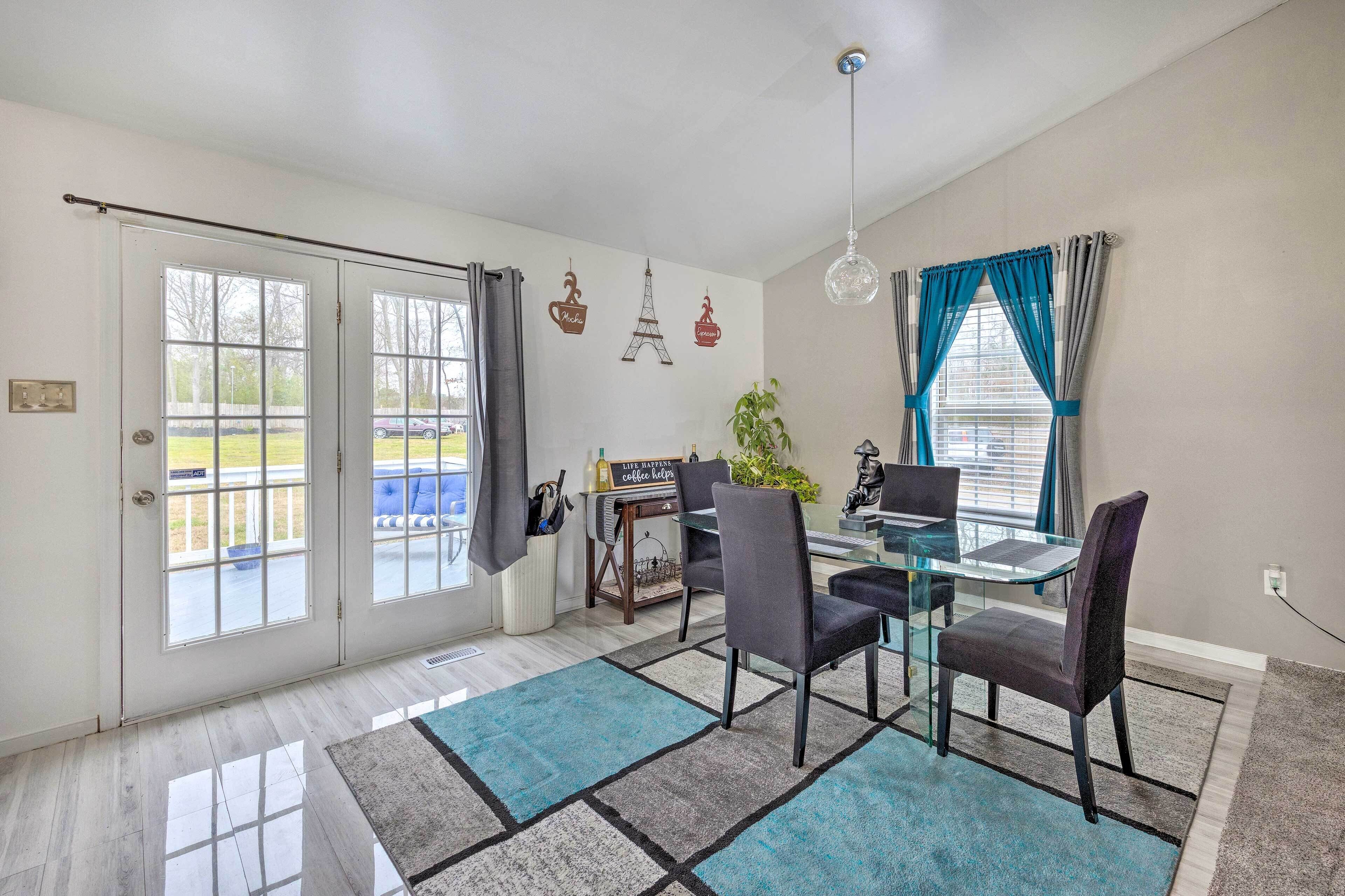 A dining area with a glass table, four chairs, a coffee table, and a hanging light fixture.