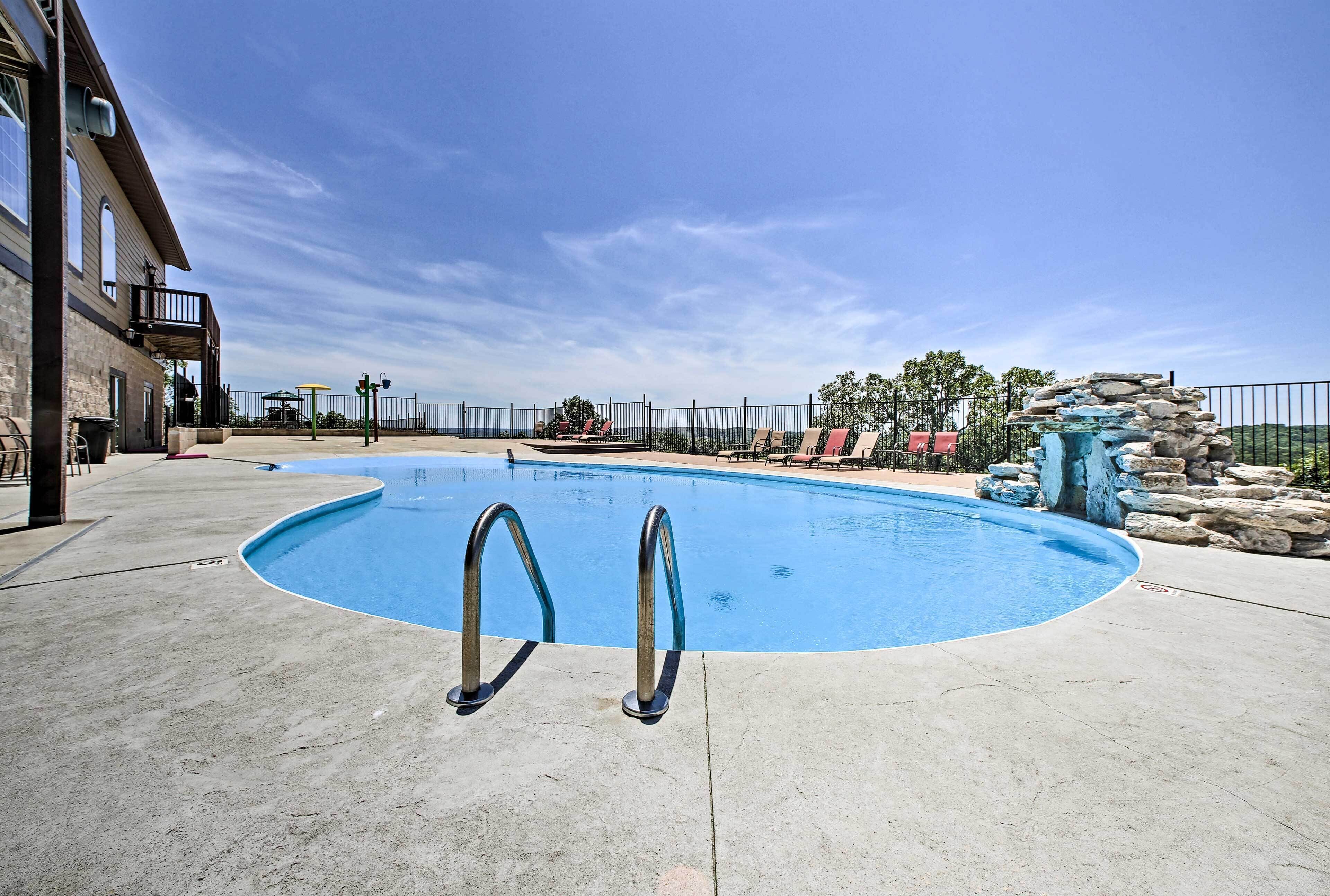 A swimming pool with two ladders, a stone structure, and a view of the surrounding area.