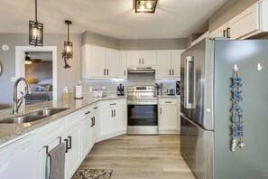 A modern kitchen with white cabinets, stainless steel appliances, and pendant lighting. - Foley Beach Cottage w/ Waterfront Backyard! (Foley)