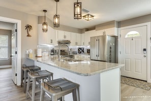 A kitchen with a central island, bar stools, stainless steel appliances, and pendant lighting. - Foley Beach Cottage w/ Waterfront Backyard! (Foley)
