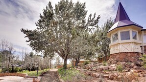 A landscaped garden with a stone pathway, a large tree, and a building with a conical roof. - 6 Mi to Red Rock State Park: Home w/ Patio & Yard (Sedona)