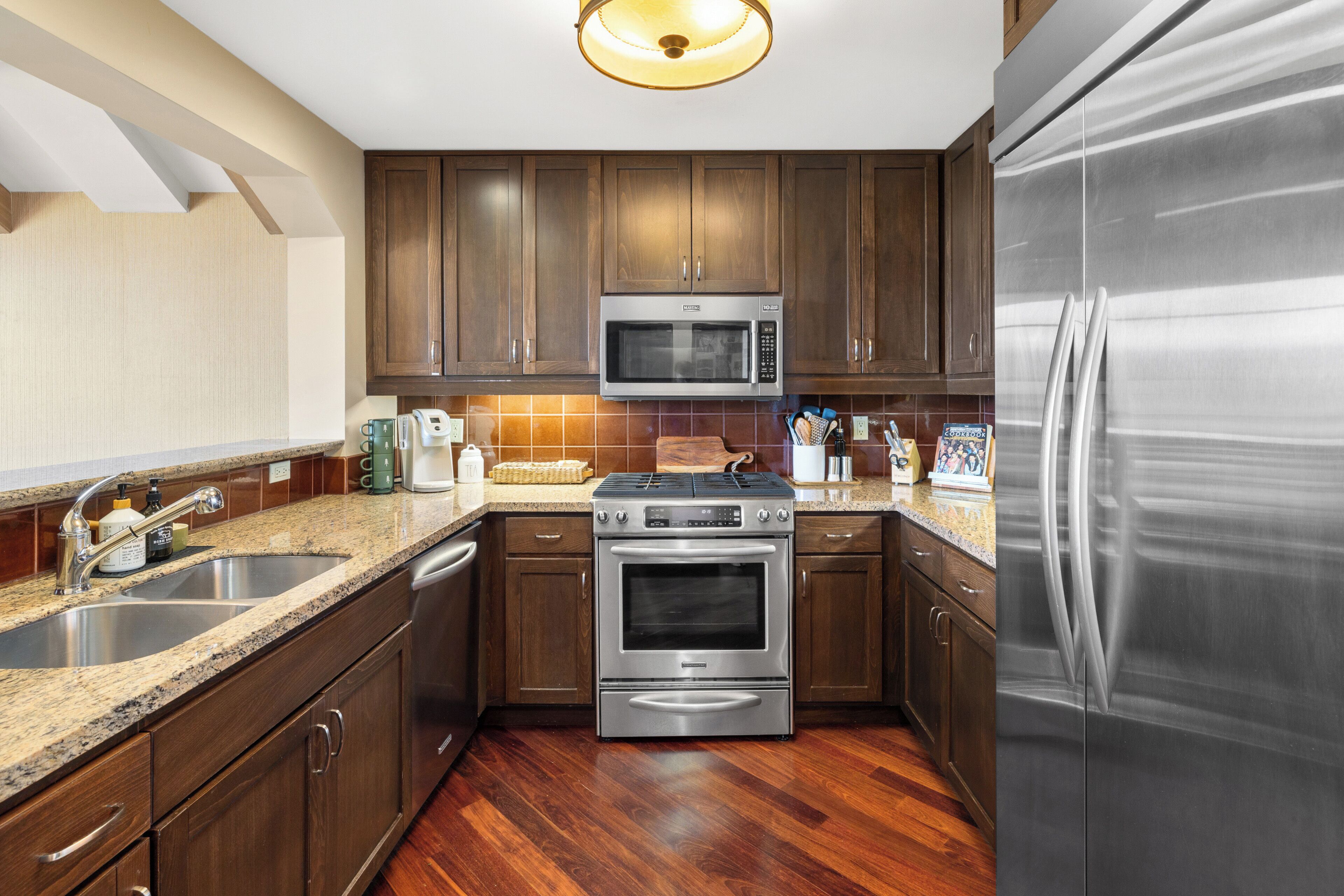 Una cocina moderna con electrodomésticos de acero inoxidable, gabinetes de madera y encimera de granito.
