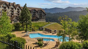 Resort com piscina, área de estar externa e montanhas ao fundo.