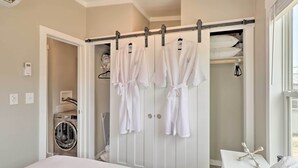 Een hotelkamer met een bed, een wasmachine, een kast met badjassen en een raam.