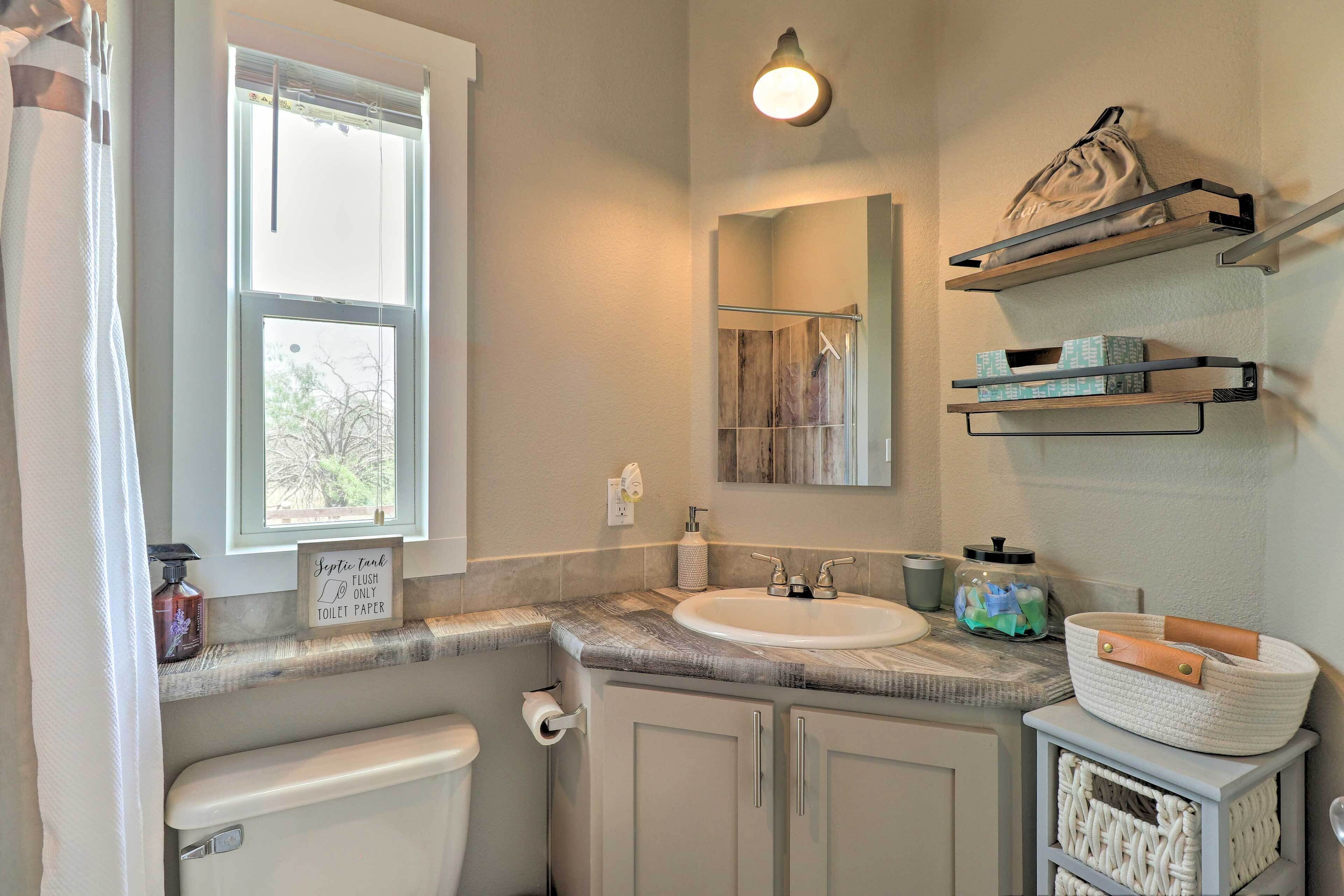 A bathroom with a toilet, sink, and shelves above the counter.