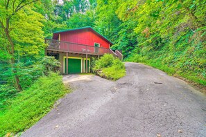 A red building with a balcony, surrounded by lush greenery. - Cozy Gatlinburg Hideaway w/ Private Hot Tub! (Gatlinburg)