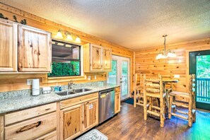 A wooden interior with a kitchen area, including cabinets, a sink, and a dishwasher. - Cozy Gatlinburg Hideaway w/ Private Hot Tub! (Gatlinburg)