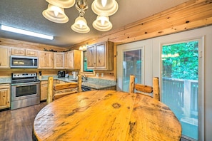 A kitchen with wooden cabinets, a stainless steel oven, a microwave, and a round wooden table with chairs. - Cozy Gatlinburg Hideaway w/ Private Hot Tub! (Gatlinburg)