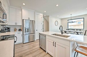 A modern kitchen with white cabinets, stainless steel appliances, and a large island with a sink.