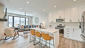 A modern kitchen with white cabinets, a central island with bar stools, a large window, and a city view. - Newly-built Lakeside Gem w/ Community Perks! (Huntsville)