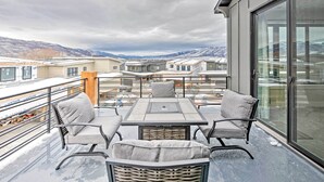 A balcony with a table and chairs, offering a view of other buildings and mountains. - Newly-built Lakeside Gem w/ Community Perks! (Huntsville)