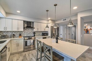 A modern kitchen with white cabinets, stainless steel appliances, and pendant lighting.