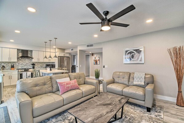 A modern living room with a sofa, a coffee table, and a ceiling fan.