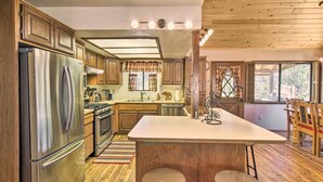 A modern kitchen with wooden cabinets, stainless steel appliances, and a central island with stools. - Rustic, Forest-view Retreat in Heber-overgaard! (Overgaard)