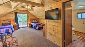 A cozy bedroom with two beds, a ceiling fan, and a TV mounted on the wall. - Rustic, Forest-view Retreat in Heber-overgaard! (Overgaard)