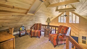 A cozy attic room with wooden walls, a ceiling fan, a table with chairs, a lamp, and a TV. - Rustic, Forest-view Retreat in Heber-overgaard! (Overgaard)
