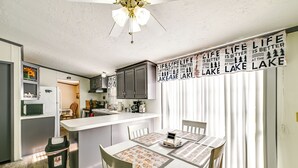 A kitchen with a central island, white cabinets, and a dining area with a table set for four. - Quiet 'horseshoe Hill House' By Lake Barkley! (Cadiz)