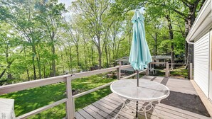 A wooden deck with a round table and a blue umbrella, overlooking a grassy yard and trees. - Quiet 'horseshoe Hill House' By Lake Barkley! (Cadiz)