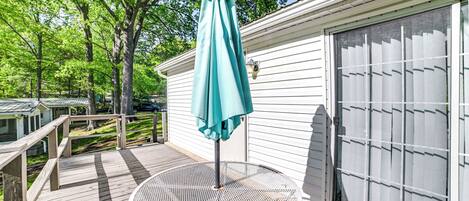 A wooden deck with a metal table and a teal umbrella.