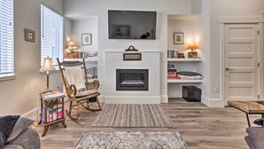 A living room with a fireplace, a television mounted above it, and a bookshelf. - Boise Townhome w/ Rooftop Deck, 2 Mi to Downtown! (Boise)