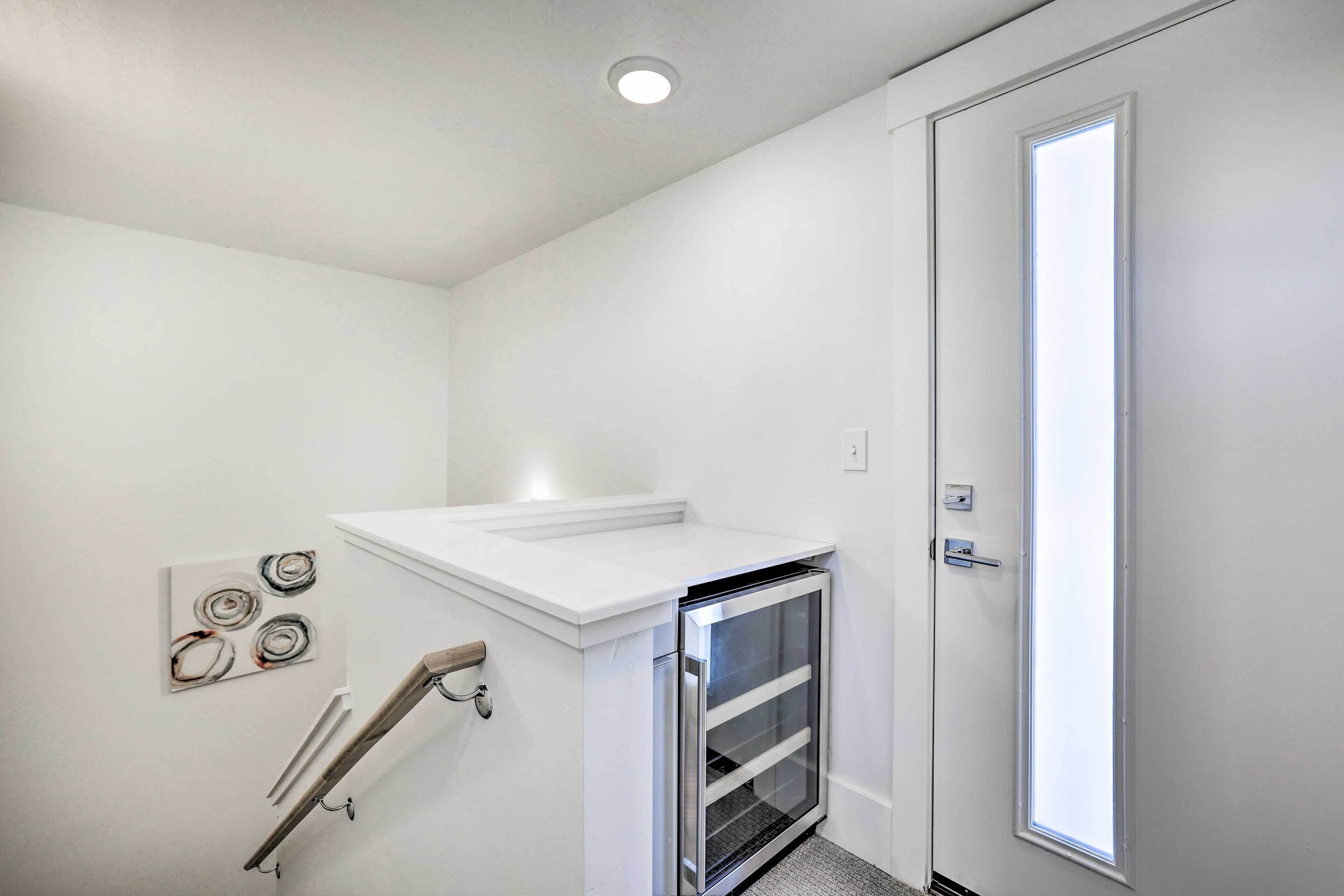 Una habitación pequeña y blanca con horno empotrado, una puerta con ventana y una obra de arte colgada en la pared.
