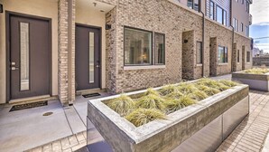 A modern building with a brick facade, large windows, and a welcome mat at the entrance. - Boise Townhome w/ Rooftop Deck, 2 Mi to Downtown! (Boise)