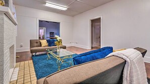 Een woonkamer met een bank, een bijzettafeltje en een blauw vloerkleed.