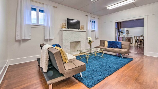 Een woonkamer met een open haard, twee banken, een salontafel en een aan de muur bevestigde televisie.