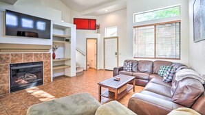 A living room with a fireplace, a leather sofa, a coffee table, and a flat-screen TV mounted above the fireplace. - Cave Creek Retreat w/ Private Pool & Hot Tub! (Cave Creek)