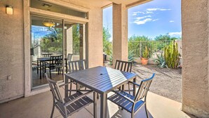 An outdoor patio with a table and chairs, a glass door leading to a covered area, and a view of cacti and trees. - Cave Creek Retreat w/ Private Pool & Hot Tub! (Cave Creek)