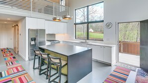 A modern kitchen with a large island, bar stools, a built-in stove, and a large window offering a view of the outdoors. - Nature Lovers' Paradise! Luxe Retreat w/ Game Room (Salem)