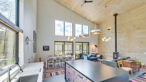 A modern kitchen with a central island, large windows, and a dining area with a sofa and table. - Nature Lovers' Paradise! Luxe Retreat w/ Game Room (Salem)