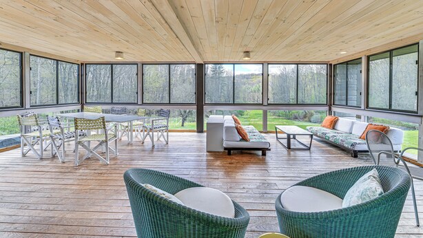 A covered outdoor area with a wooden ceiling, large windows, a dining table with chairs, a sofa, and wicker chairs. - Nature Lovers' Paradise! Luxe Retreat w/ Game Room (Salem)