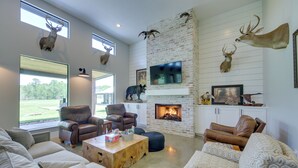 A spacious living room with a fireplace, leather sofas, and mounted animal heads on the walls.
