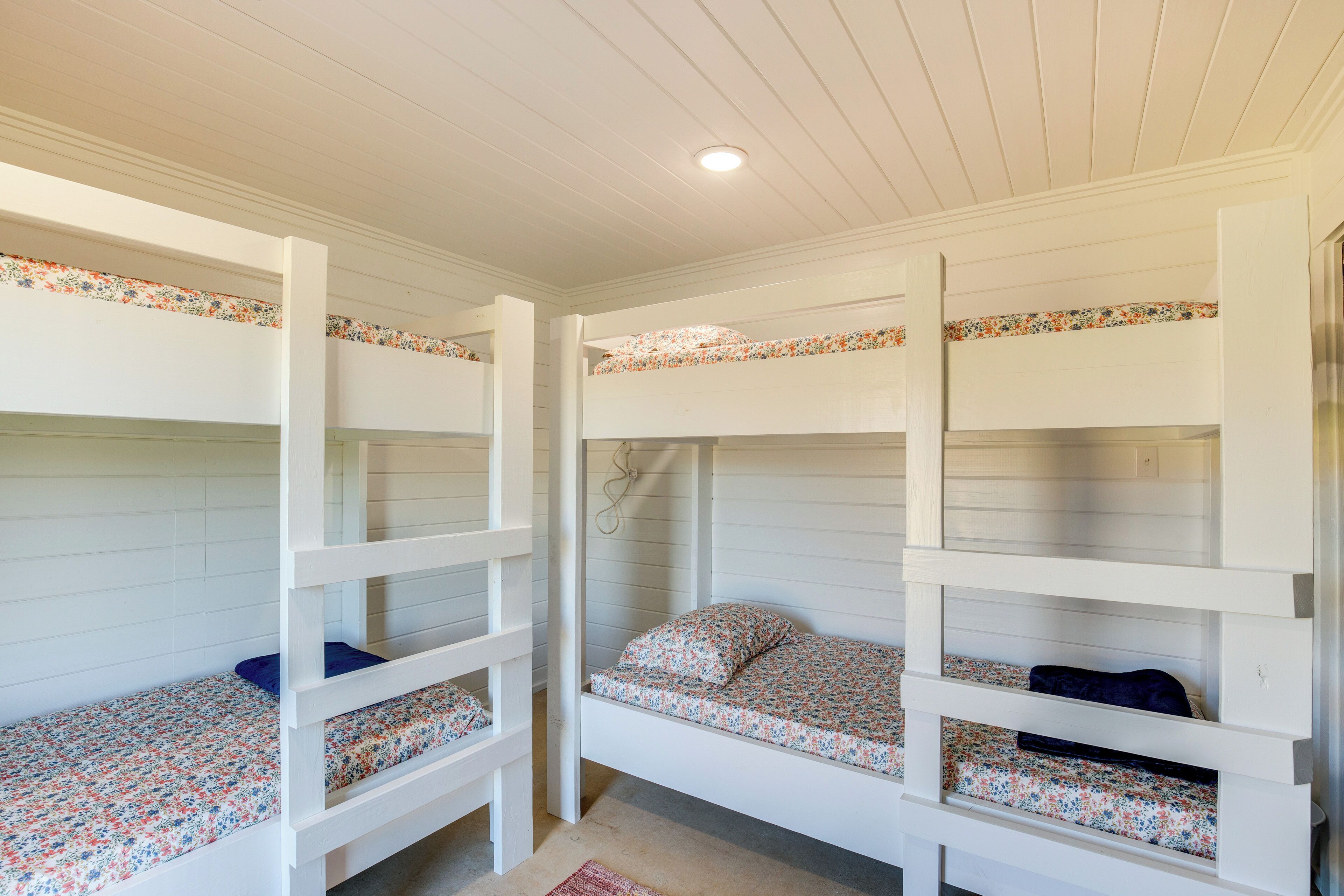Une chambre avec des lits superposés, chacun doté d’un matelas à motifs floraux et d’un oreiller bleu.