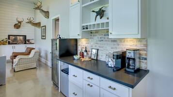 A kitchen with white cabinets, a coffee maker, and mounted animal heads.