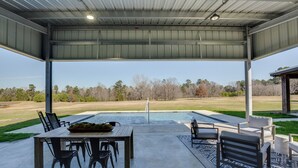 An outdoor patio with a pool, seating, and a view of the surrounding landscape.