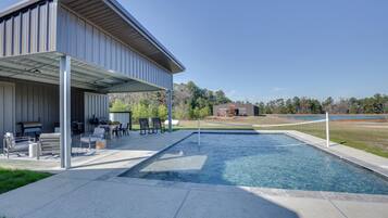 A pool area with a covered patio, outdoor seating, and a view of the surrounding landscape.