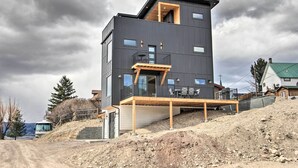 A modern two-story building with a balcony, a wooden deck, and a view of the surrounding landscape. - Exquisite Discovery Mtn Home w/ Sweeping Views! (Philipsburg)