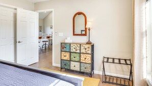 Een kamer met een witte deur, een spiegel, een kast met verschillende vakken en een zwart rek.