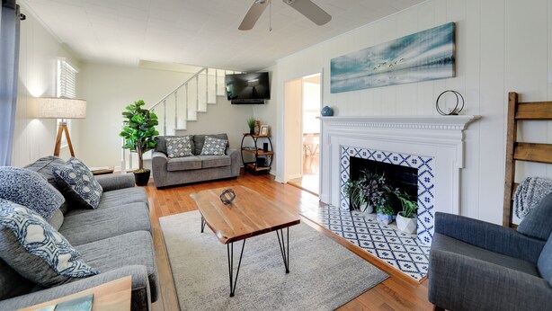 A spacious living room with a fireplace, a ceiling fan, and a television mounted on the wall. - North Carolina Retreat - Deck, Grill & Creek Views (Beaufort)