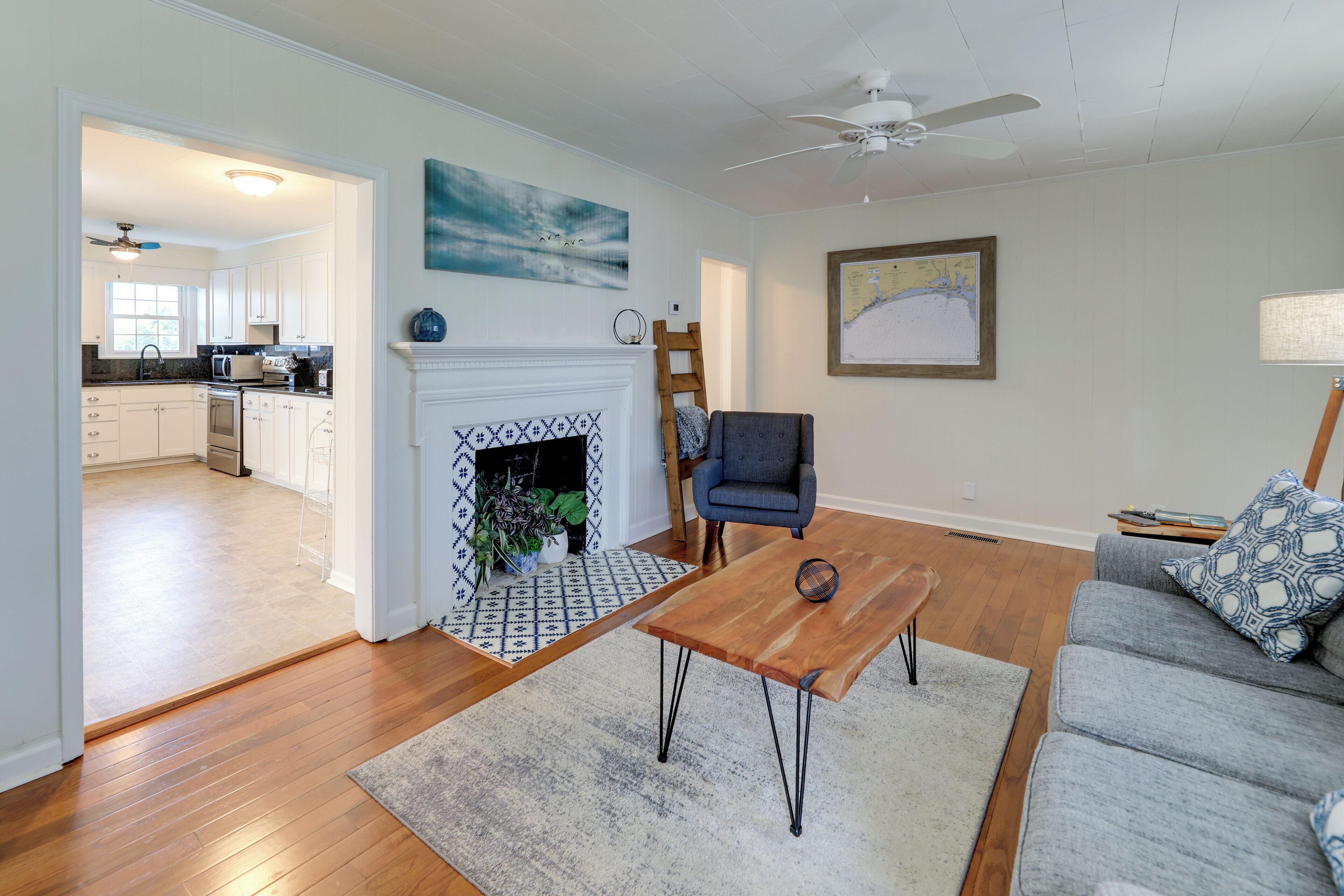 A living room with a fireplace, a sofa, a coffee table, and a view into the kitchen.
