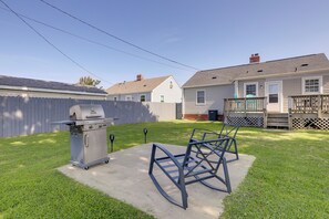 Ein Garten mit Grill, einer Metallkonstruktion und einer Holzterrasse.